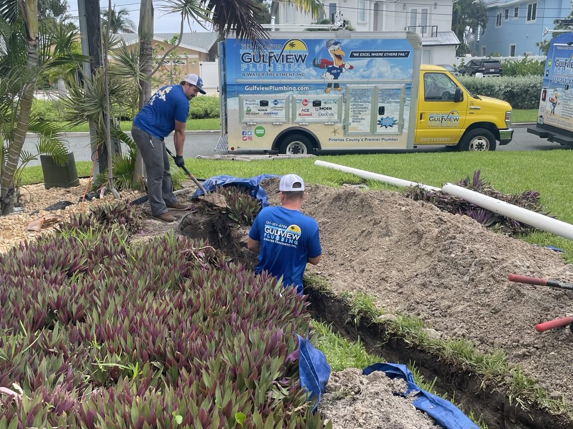 Gulfview technicians working in an excavated trench beside a company service truck