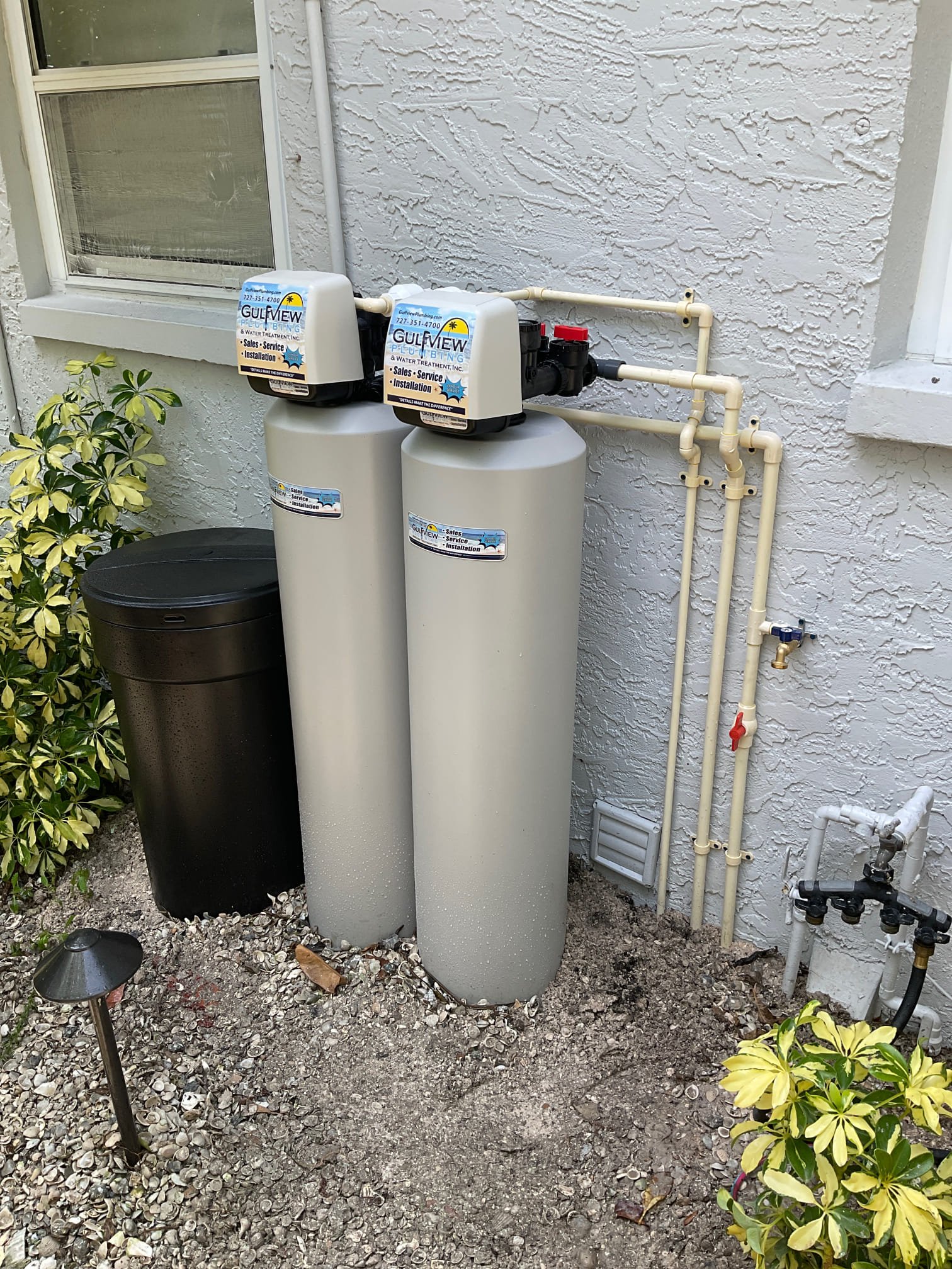Two Gulfview-branded treatment tanks and a separate brine container beside an exterior wall