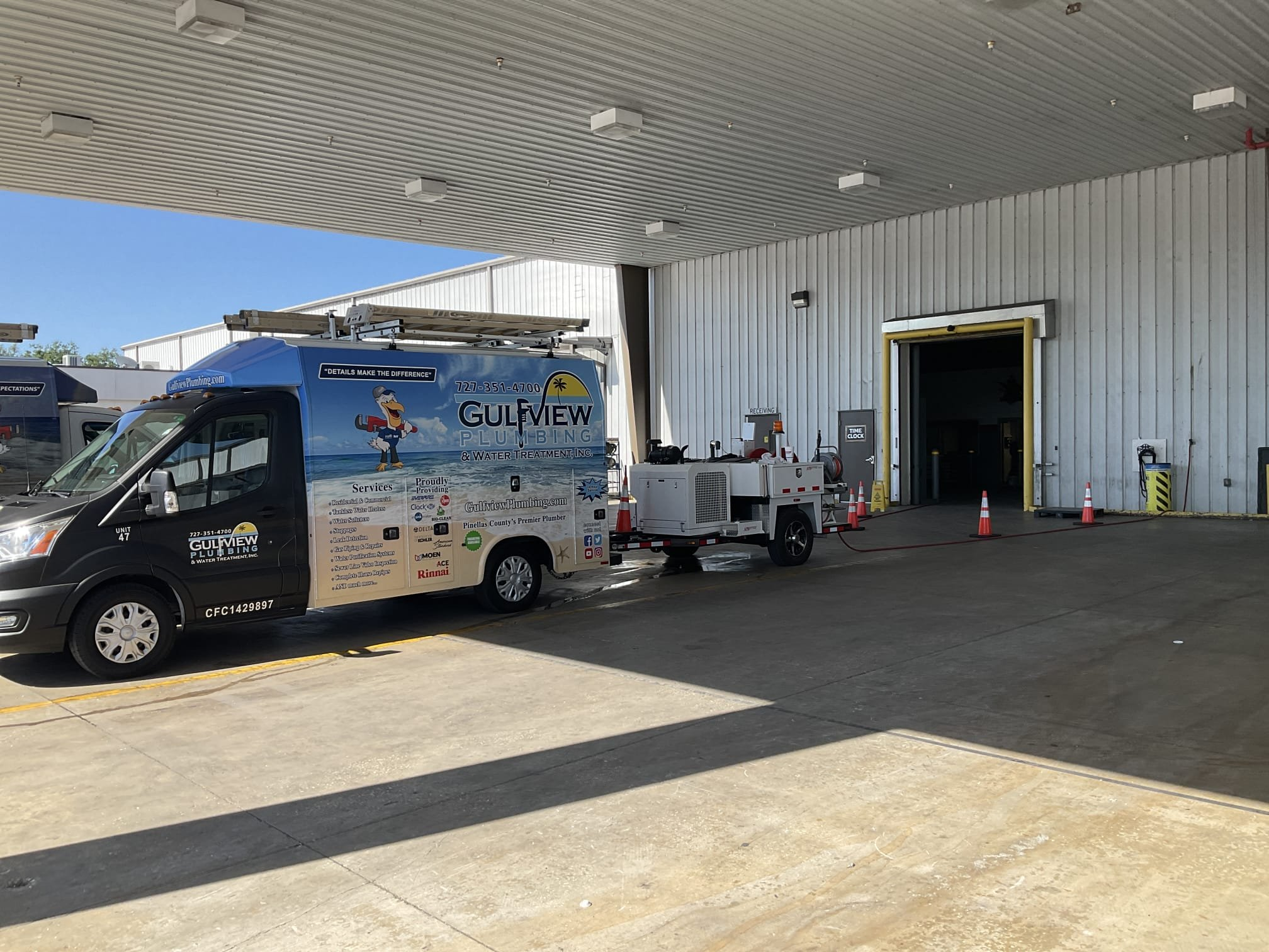 Gulfview service truck and trailer-mounted equipment beside a warehouse loading entrance with traffic cones