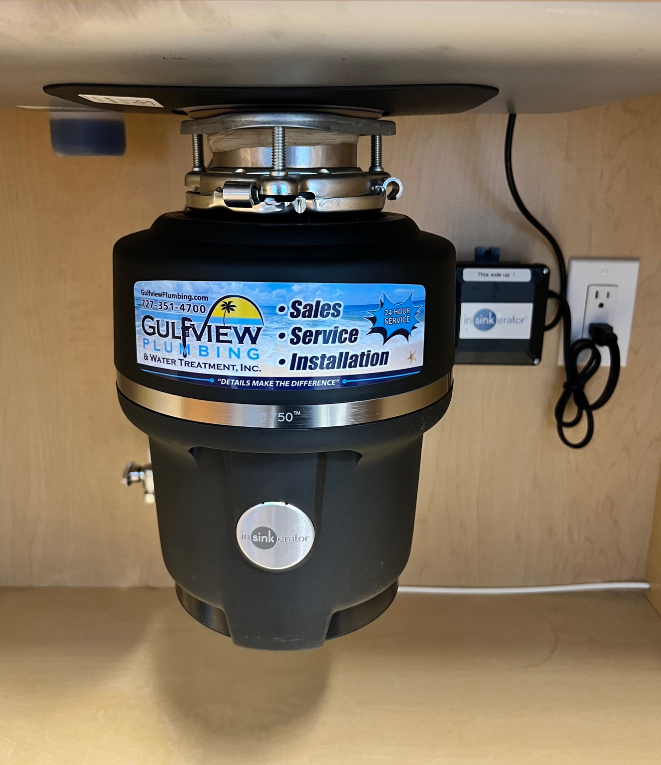InSinkErator PRO750 garbage disposal beneath a kitchen sink with a Gulfview Plumbing service sticker