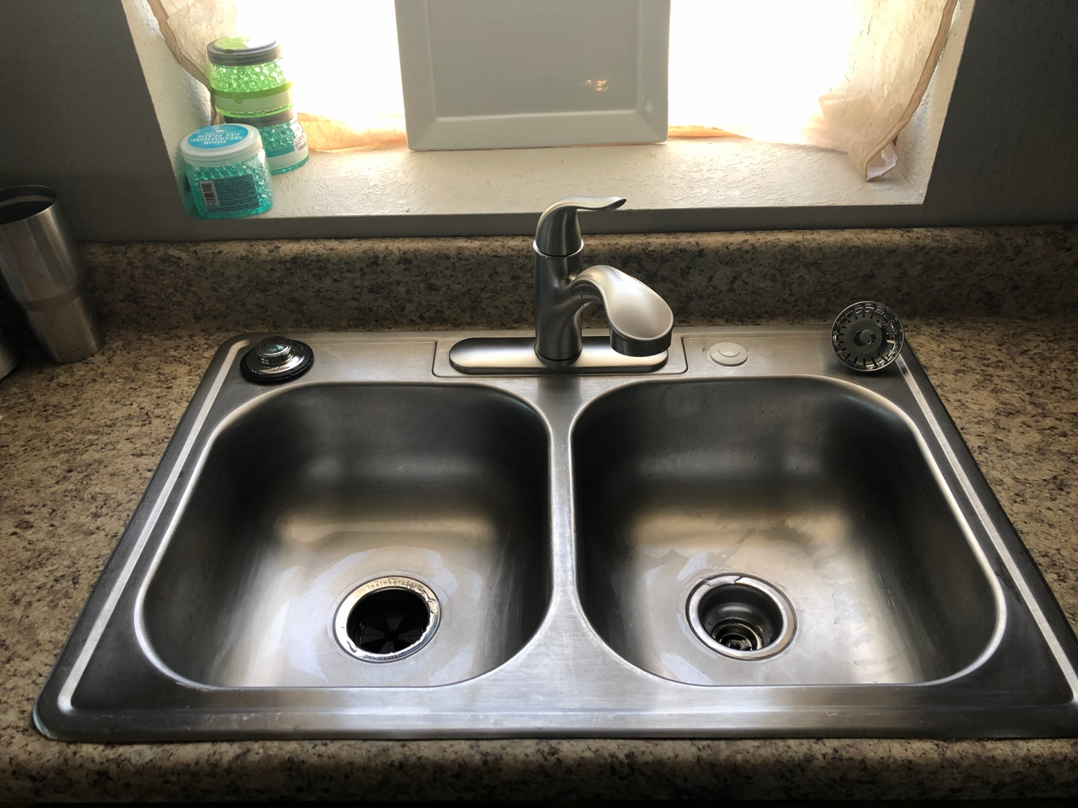 Brushed-metal single-handle kitchen faucet above a double stainless-steel sink