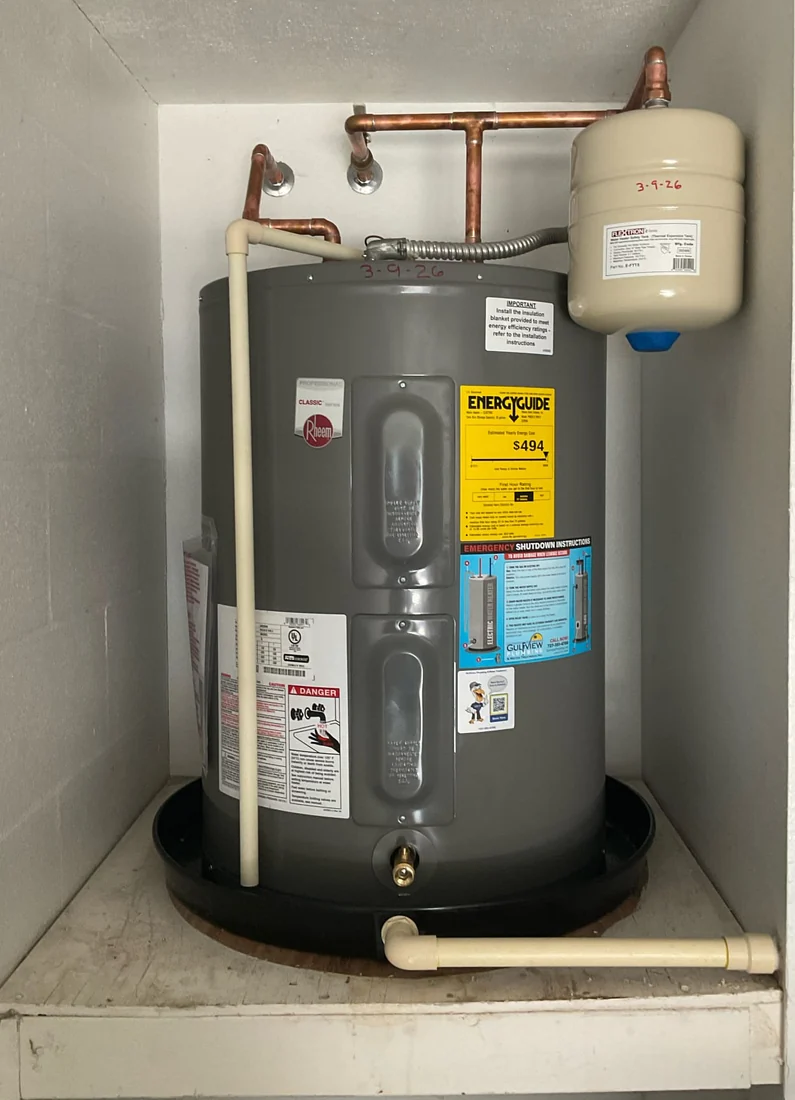 Compact Rheem tank water heater with an expansion tank, copper connections and a drain pan