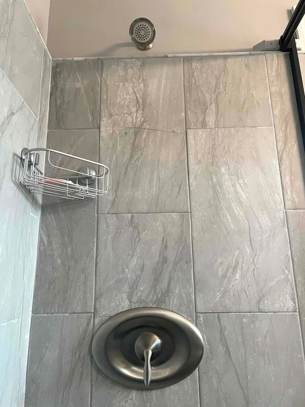 Metal shower head and single-handle control against marble-look shower tile