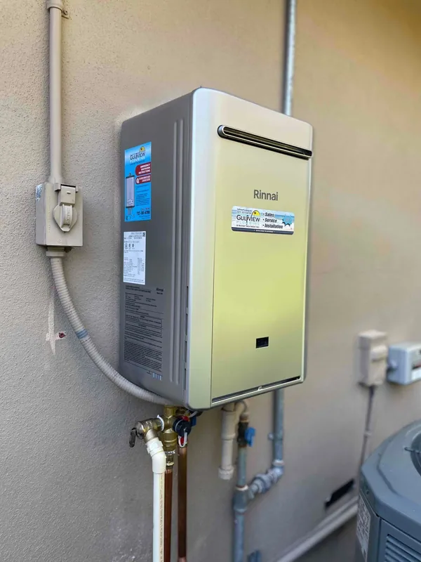Rinnai tankless water heater with service valves and piping on a light stucco wall
