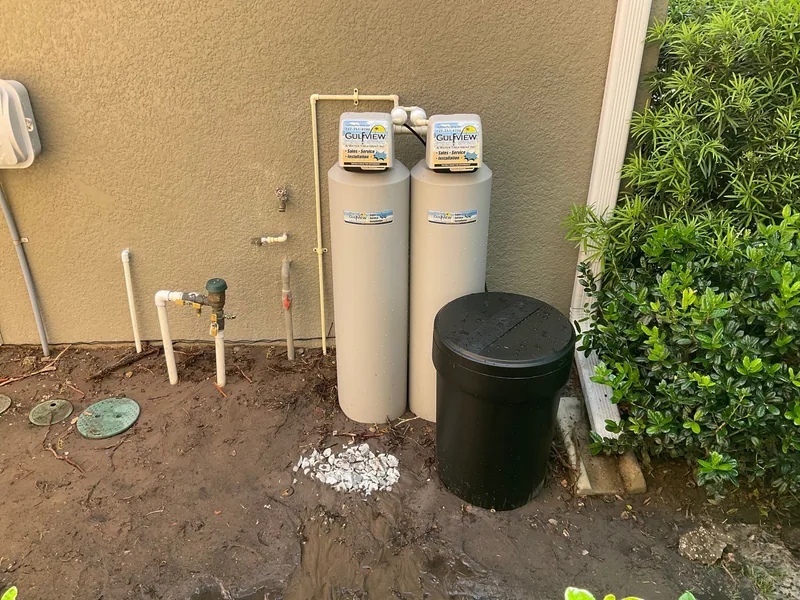 Two Gulfview treatment tanks and a black brine container beside a tan exterior wall