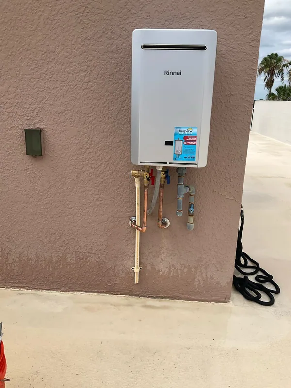 Rinnai tankless water heater with copper connections on a brown stucco wall