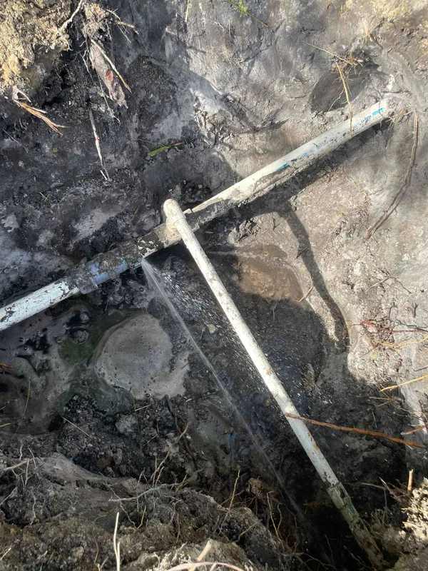 Water spraying from an exposed pipe connection in an excavated soil trench