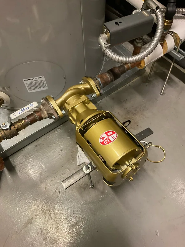 Gold Bell and Gossett circulation pump connected to piping beside a commercial hot-water tank