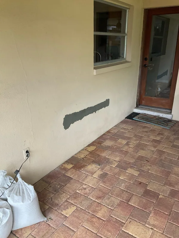 Unpainted horizontal wall patch beneath a window beside a brown-framed door