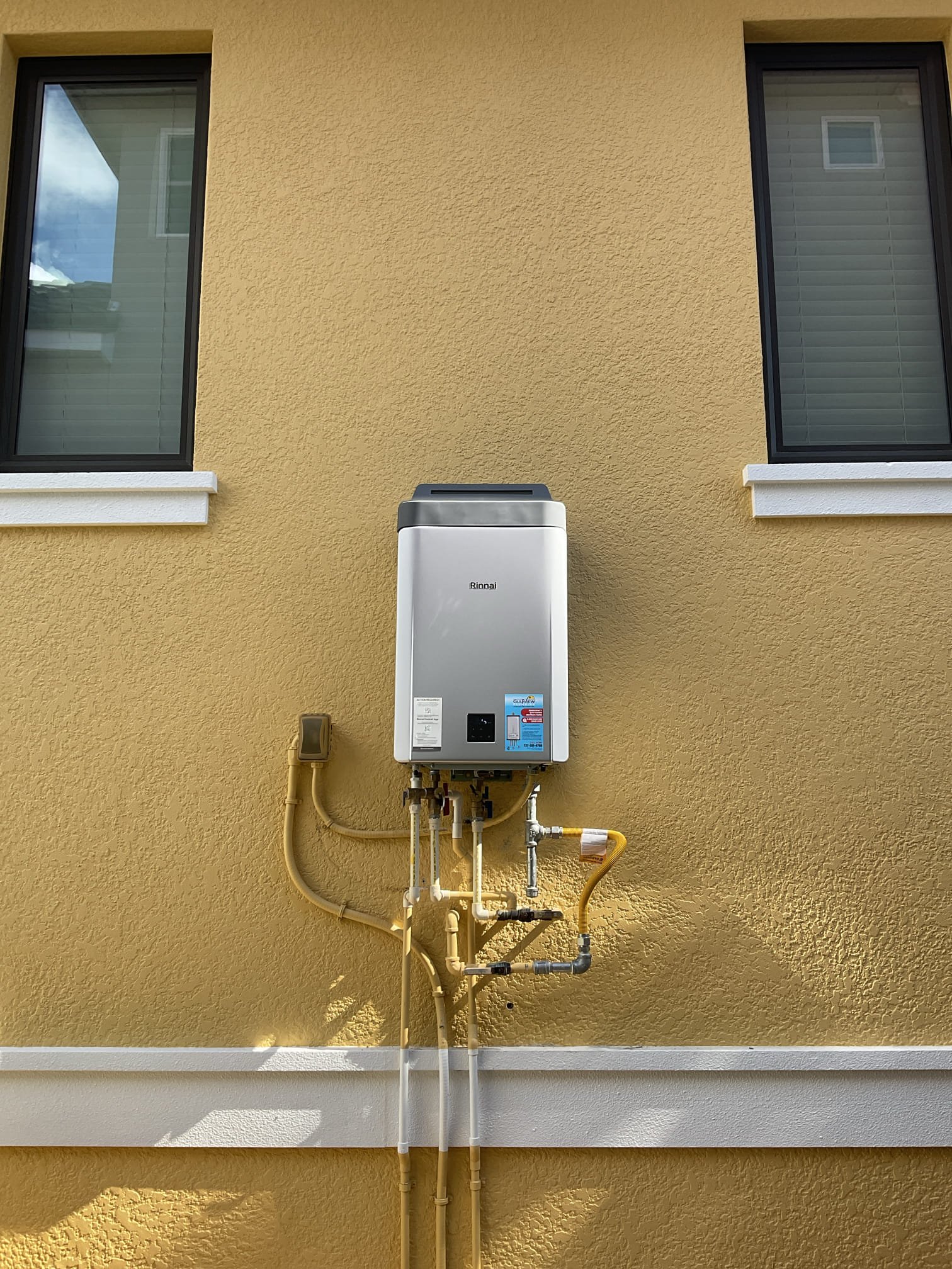 Rinnai tankless water heater on an exterior wall with connected piping