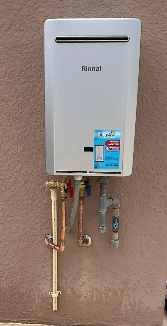 Rinnai tankless water heater with copper connections on a brown stucco wall