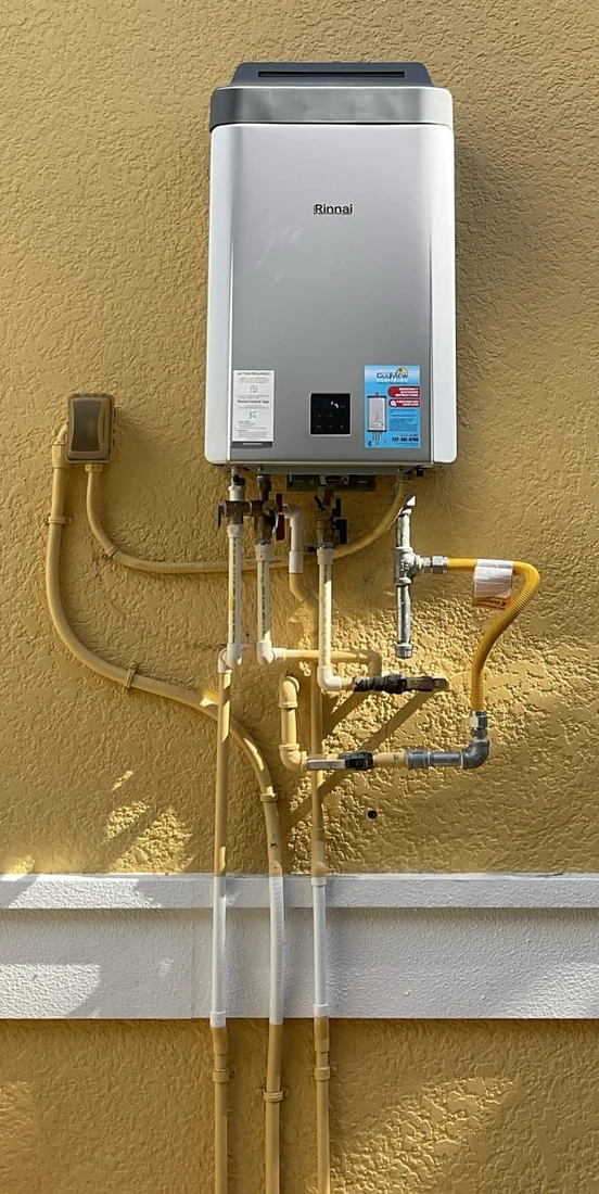Wall-mounted Rinnai water heater and service connections on a yellow wall.