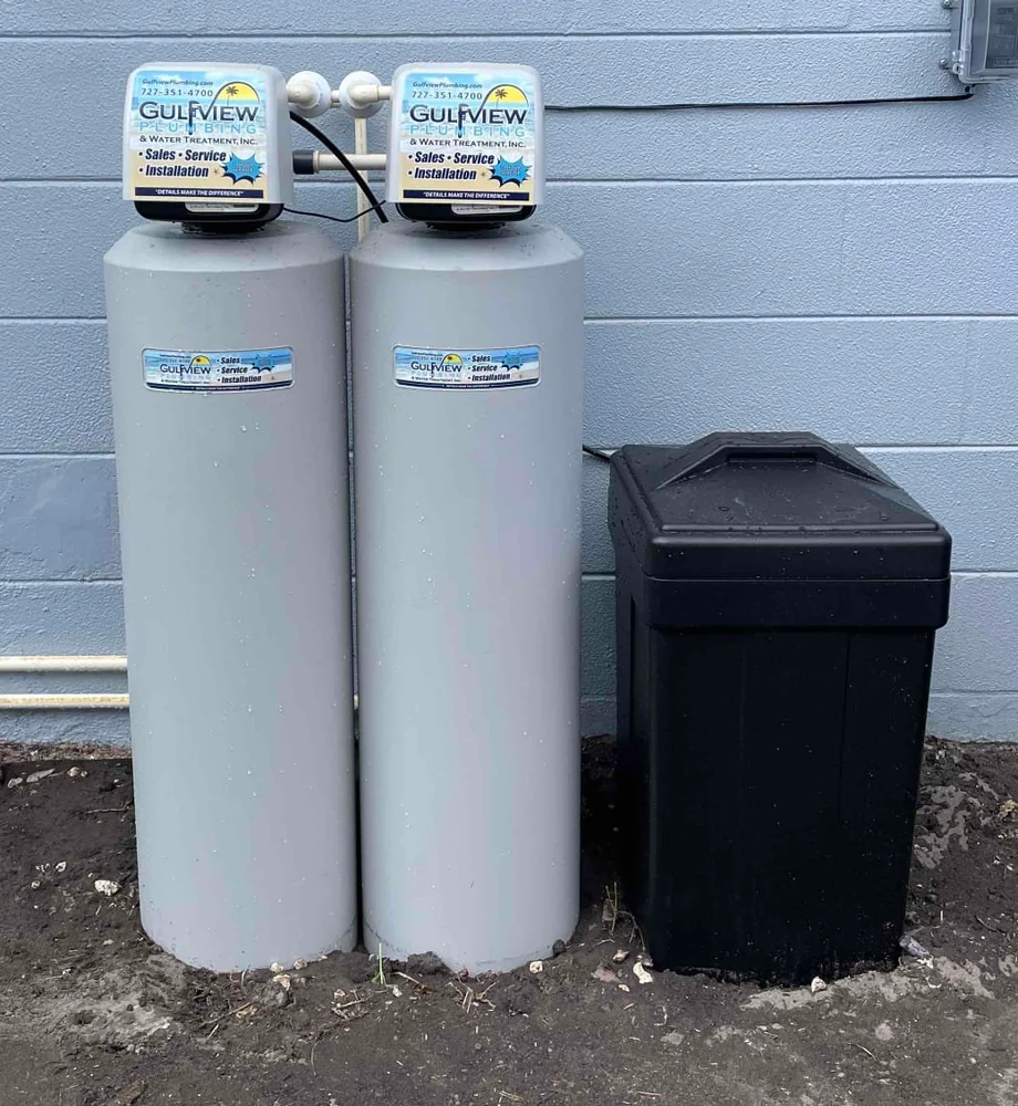 Two Gulfview-branded water-treatment tanks and a black brine container beside a gray exterior wall