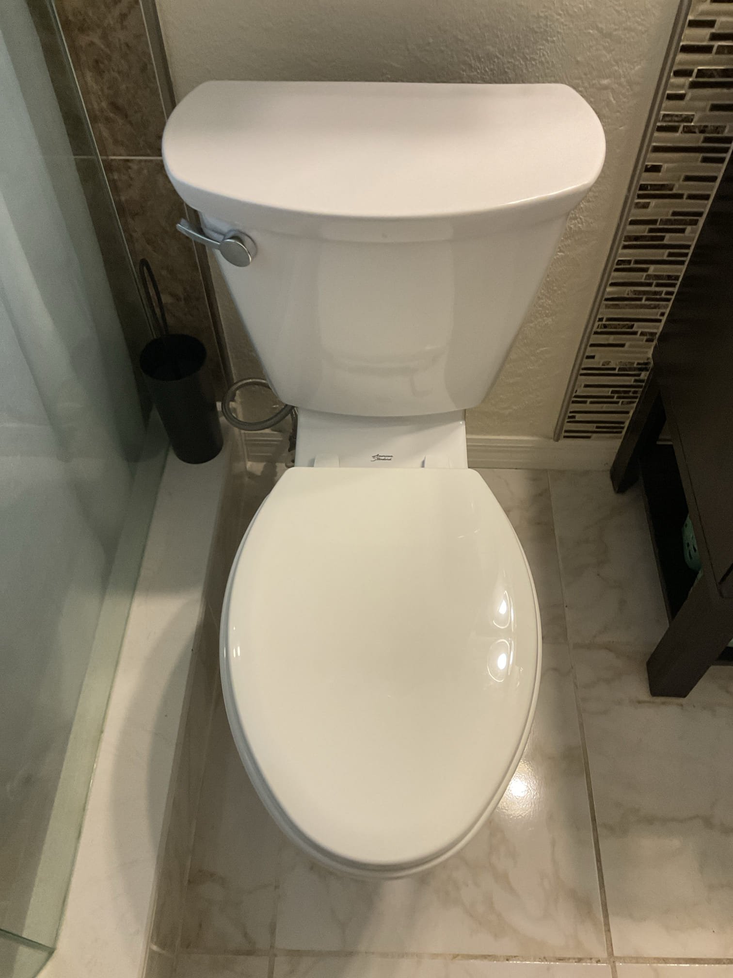 White toilet with closed lid beside a glass shower enclosure