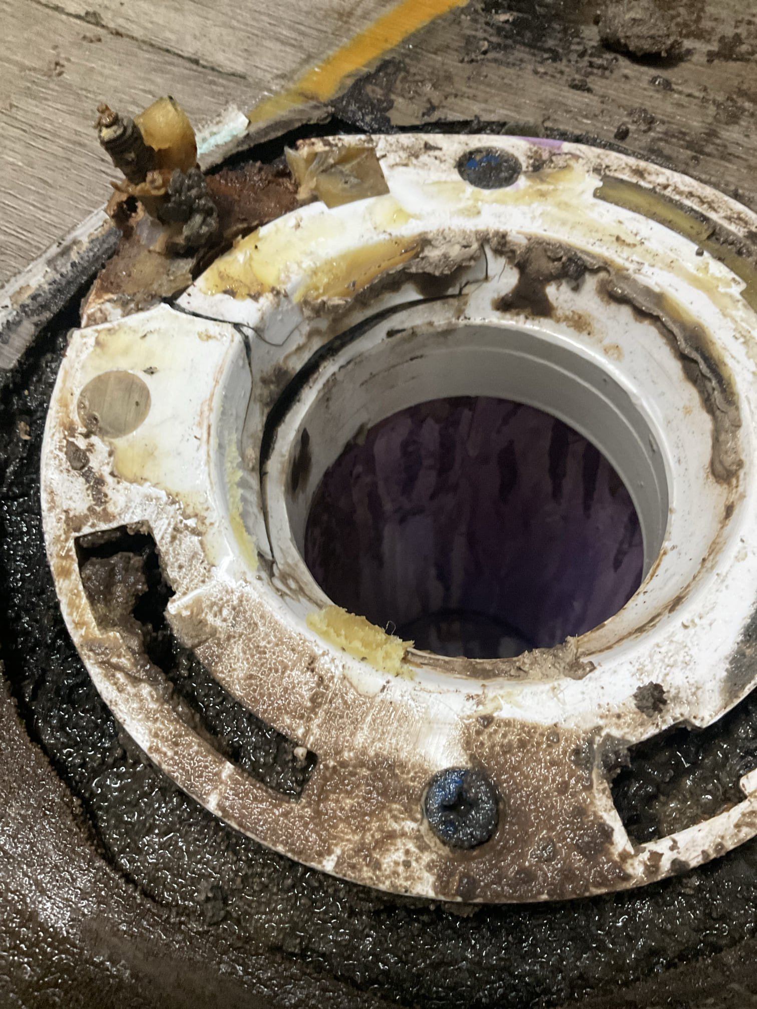 Cracked toilet flange exposed beneath a removed toilet