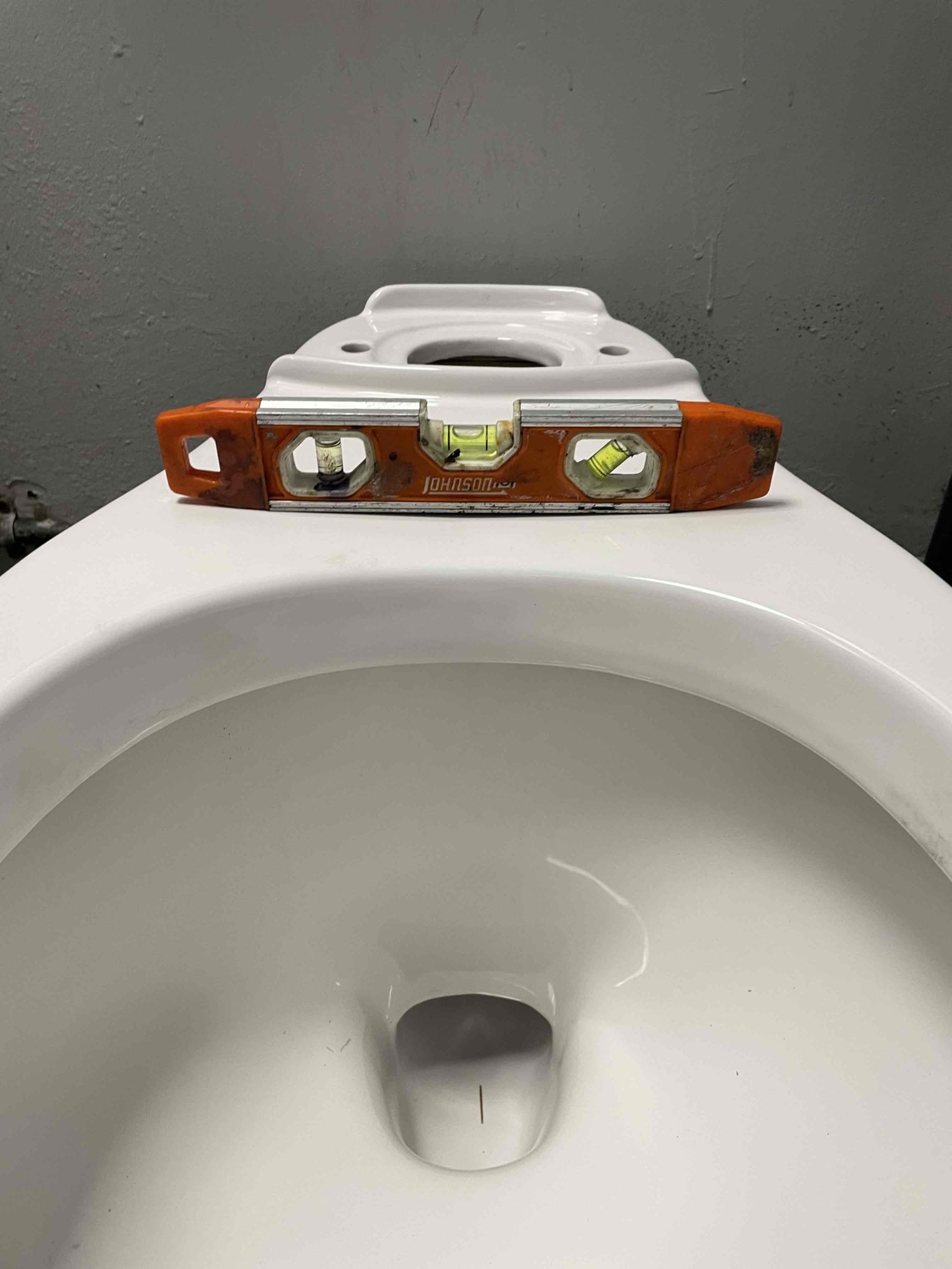 Spirit level across a toilet bowl during installation