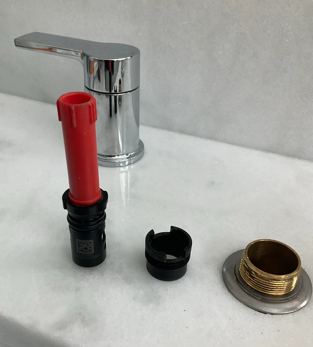 Bathroom faucet components beside a chrome handle on a white counter