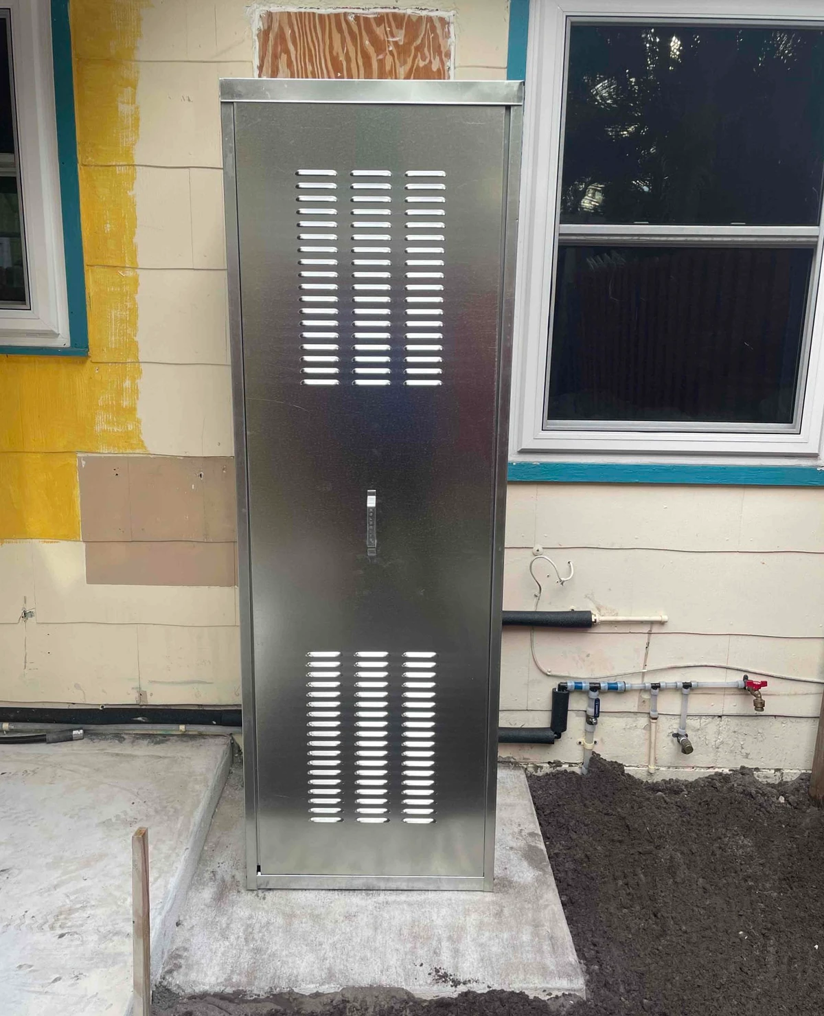 Outdoor metal water heater enclosure with its louvered front door closed