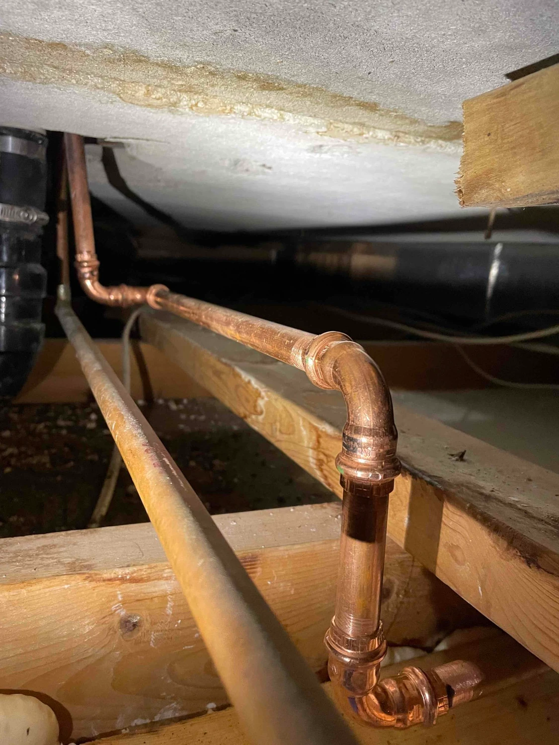 Repaired copper water line and fittings visible through the ceiling access