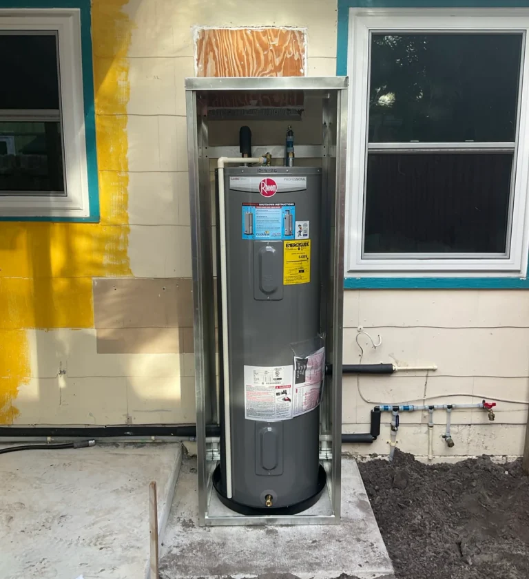 Rheem tank water heater installed inside an open outdoor metal enclosure