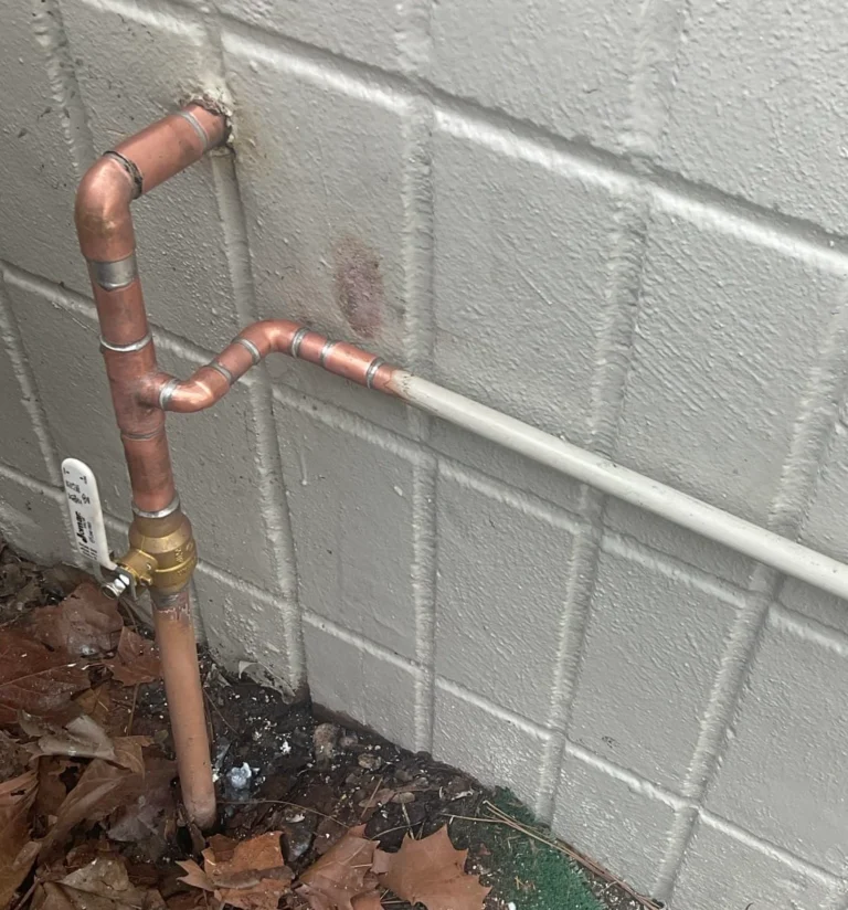 Replacement brass shutoff valve and reworked copper water piping beside an exterior block wall